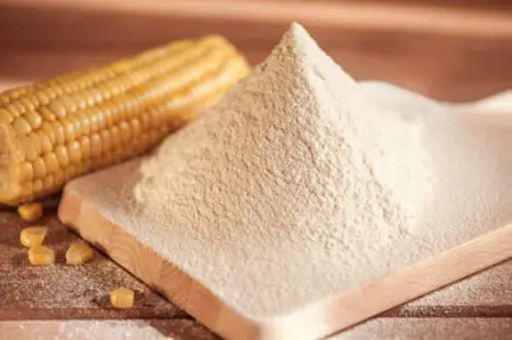 corn flour and corn on the cob on a wooden table